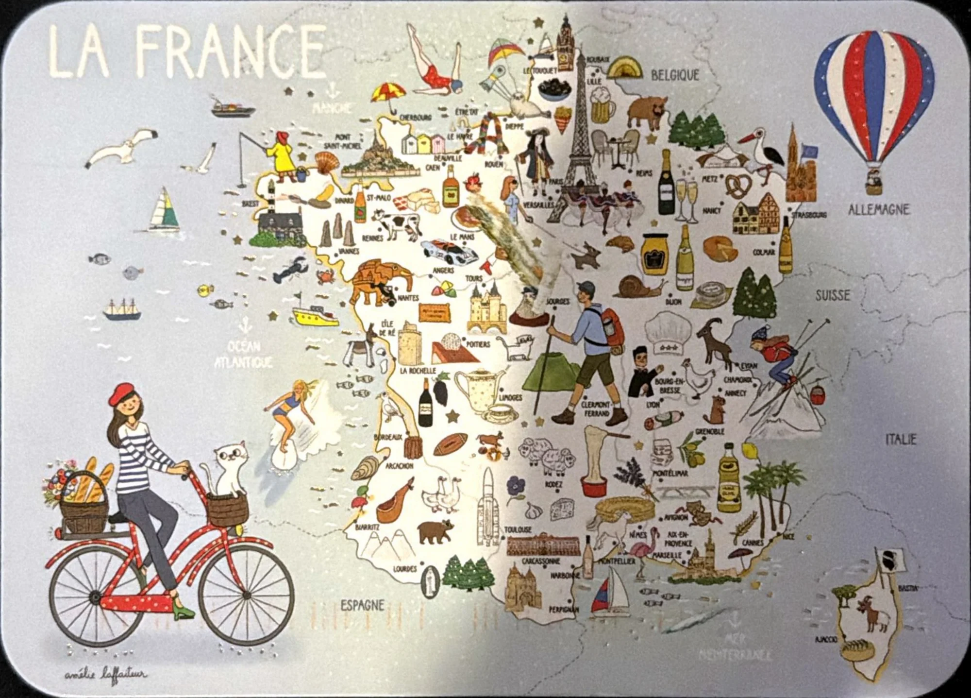 Illustrated map of France crowded with landmarks, food and people, a woman on a red bicycle and a hot-air balloon.
